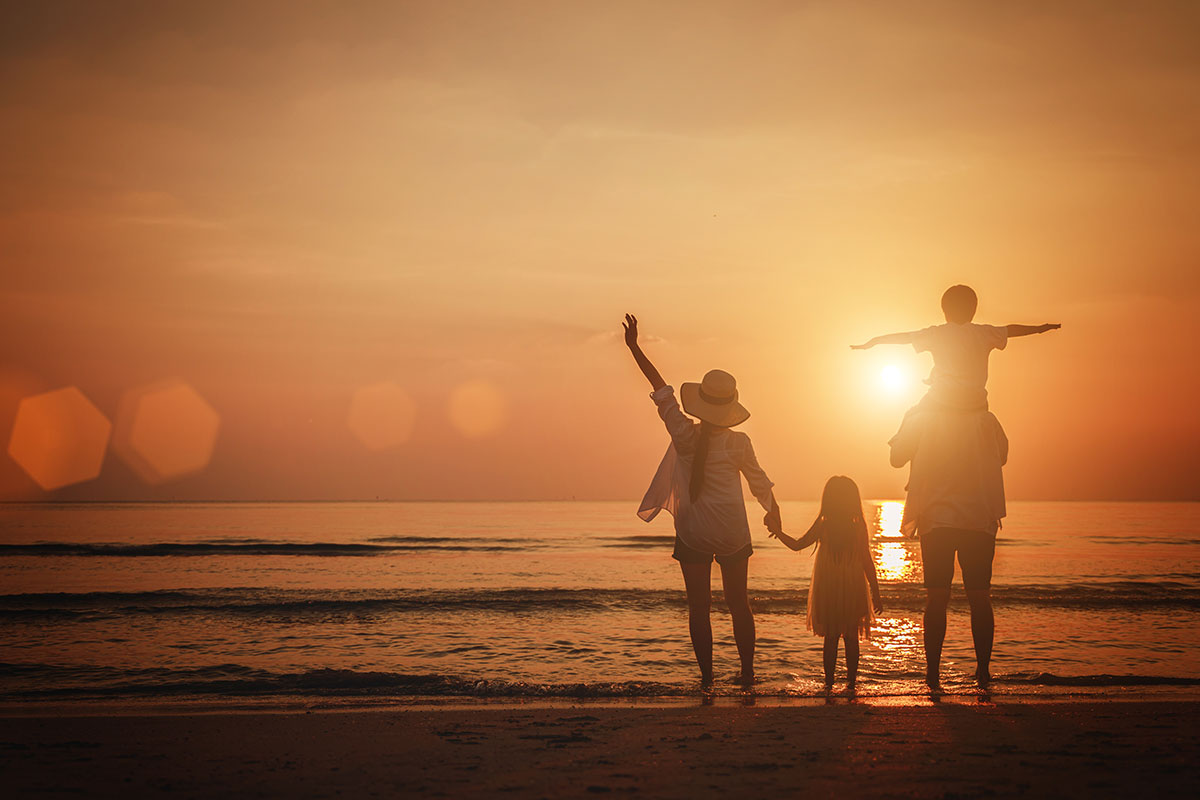 family holding hands by the beach watching sunset